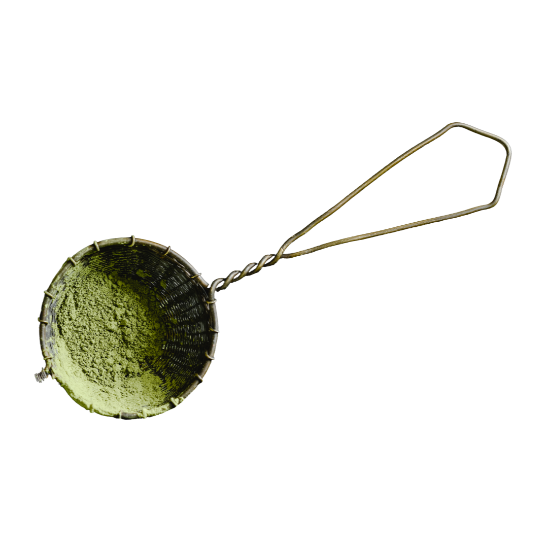 Tea strainer with green powder on a white background